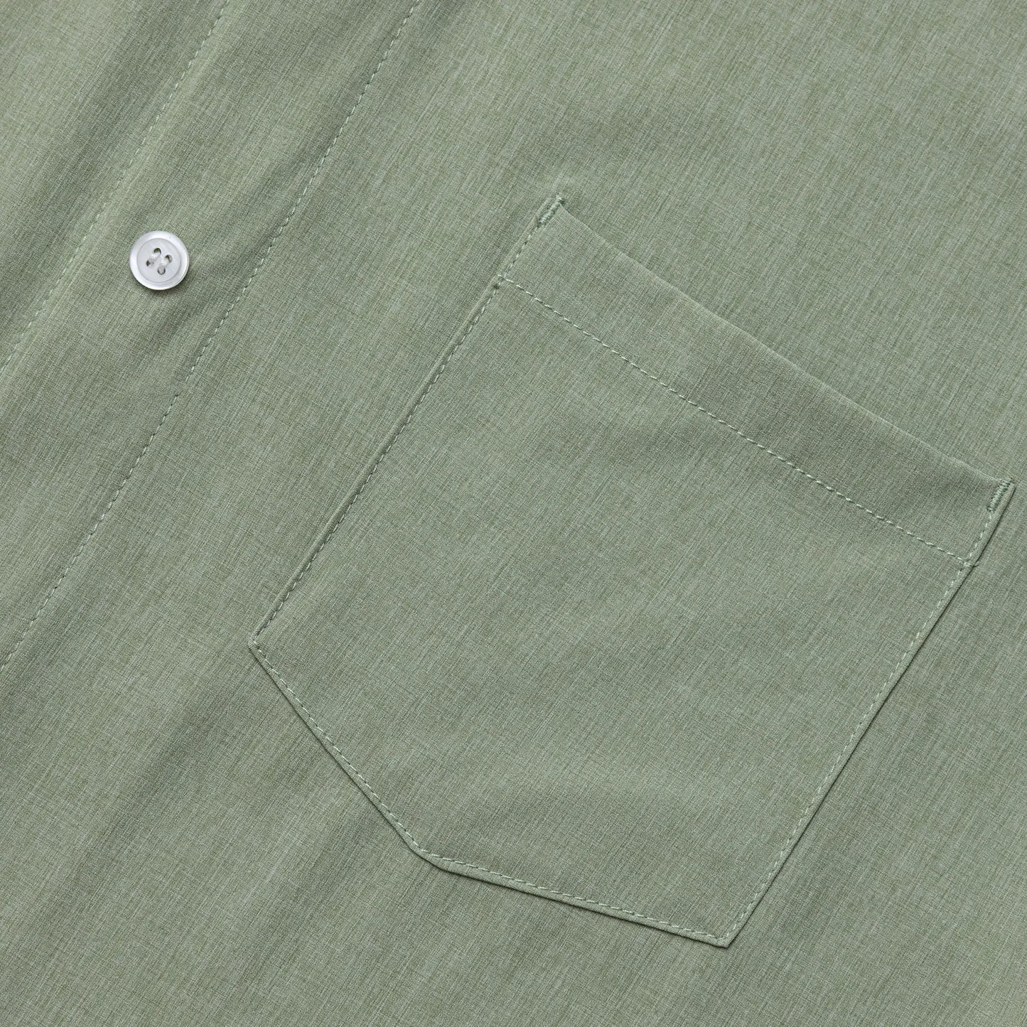 Close-up of a green shirt pocket with a button on a matching fabric background #Sage Green