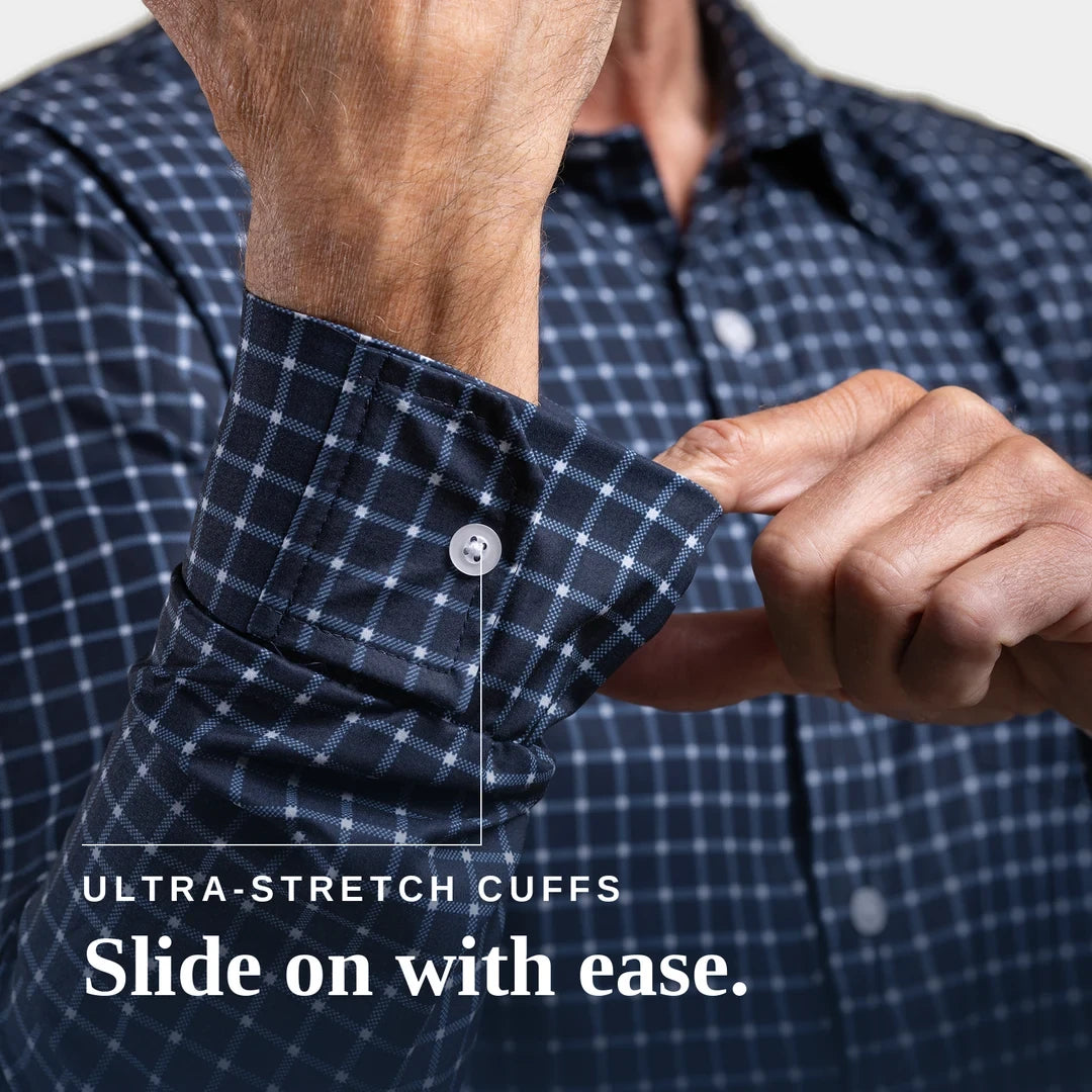 Close-up of a man wearing a navy and white checkered shirt, demonstrating the stretch of the cuff by sliding his hand inside the buttoned cuff. White text at the bottom reads 'ULTRA-STRETCH CUFFS Slide on with ease. Joe & Bella Everyday Magnetic Button-Down for Men | Relaxed-Fit #Navy Check