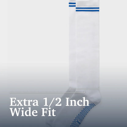 A single white sock shown against a light gray gradient background with text reading 'Extra 1/2 Inch Wide Fit.' The sock has two blue horizontal stripes near the top and a blue dotted pattern near the foot. Joe & Bella Big-Grip No-Slip Compression Socks: 3-Pack #White