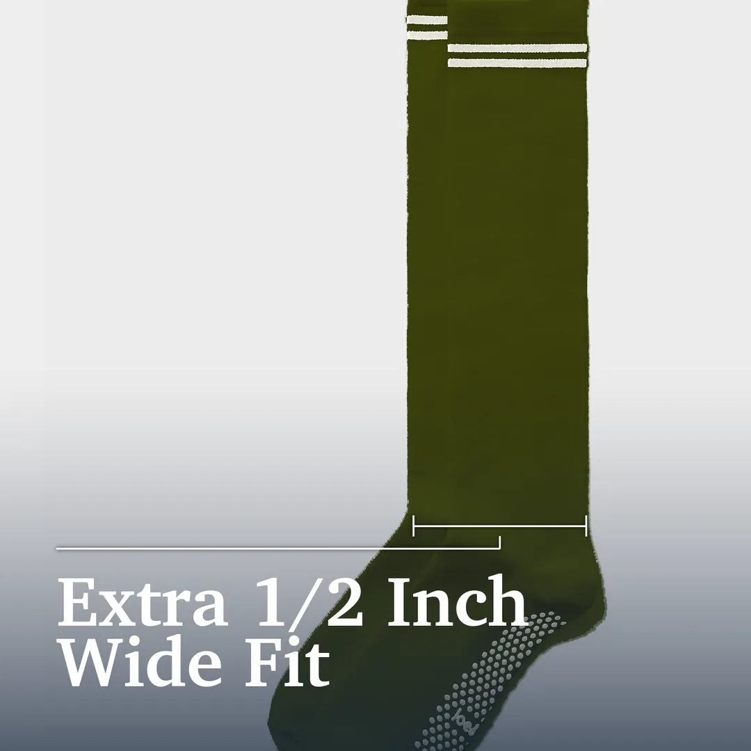 An olive green wide-fit sock with white stripes at the top and a textured grip pattern on the sole, shown against a light gray gradient background with text reading 'Extra 1/2 Inch Wide Fit'. Joe & Bella Green / REG Big-Grip No-Slip Compression Socks: 3-Pack #Green