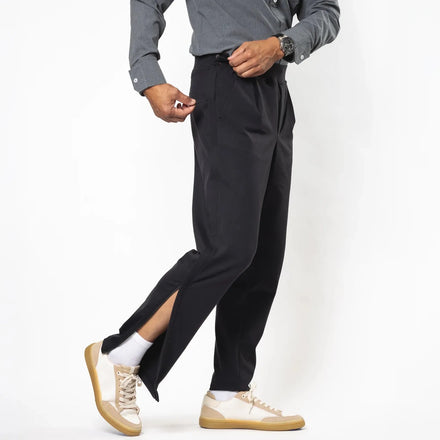 A model wearing black pinstriped trousers with a side slit, styled with a gray button-down shirt, white socks, and beige sneakers, shown from the waist down against a white studio background. Joe & Bella Black / S Everyday Side-Zip Pants for Men #Black