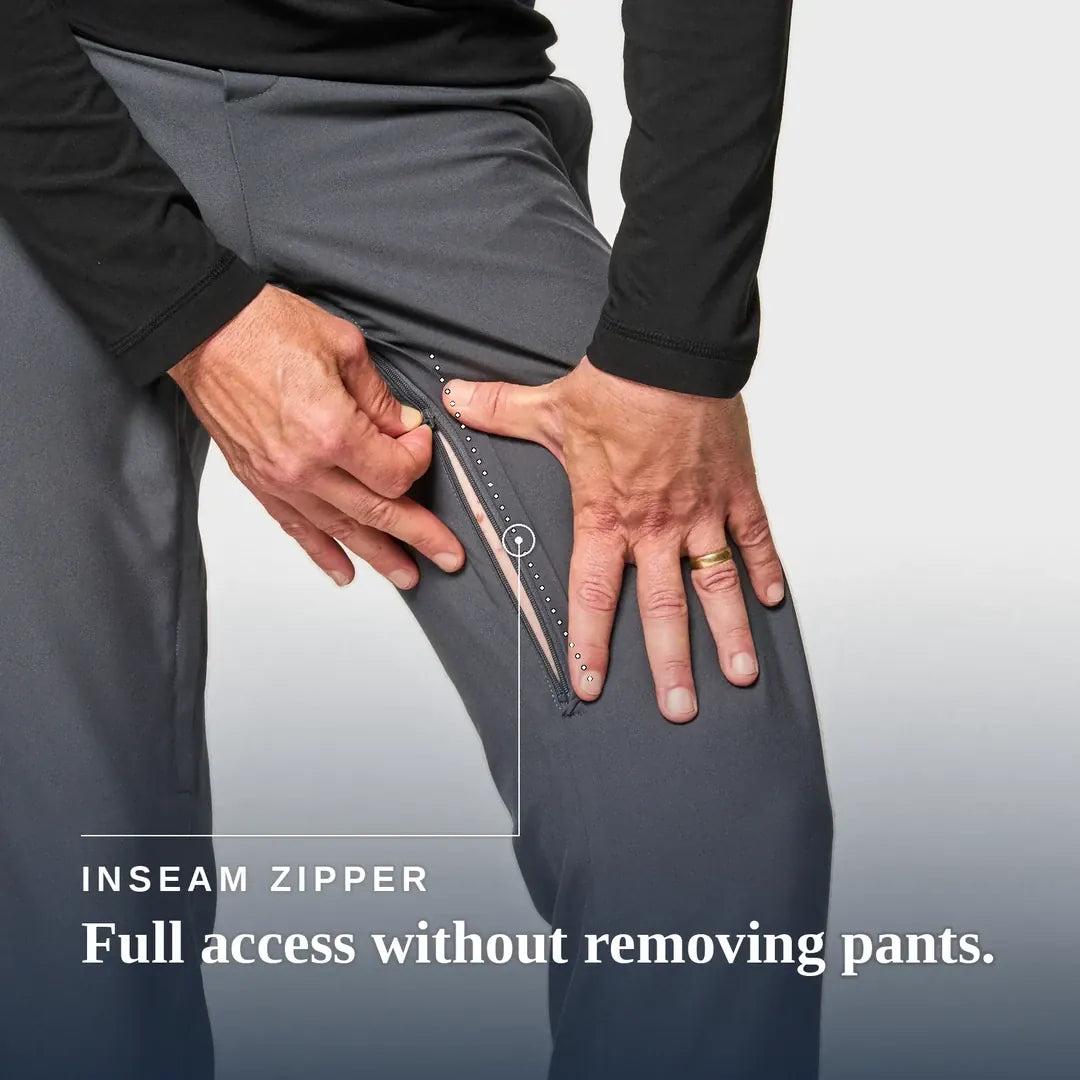 ["Close-up of a person wearing dark gray pants and a black long-sleeve top, demonstrating an inseam zipper that allows full access without removing the pants. Text at the bottom reads 'INSEAM ZIPPER Full access without removing pants. Joe & Bella CareZips® Men's Access Pants ", "Slate Grey"]