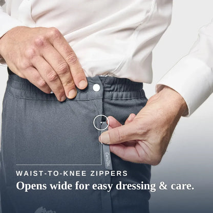 Close-up of a person wearing dark gray zippered pants, demonstrating a waist-to-knee zipper with a white shirt. Text on the image reads 'WAIST-TO-KNEE ZIPPERS' and 'Opens wide for easy dressing & care. Joe & Bella CareZips® Men's Access Pants #Slate Grey