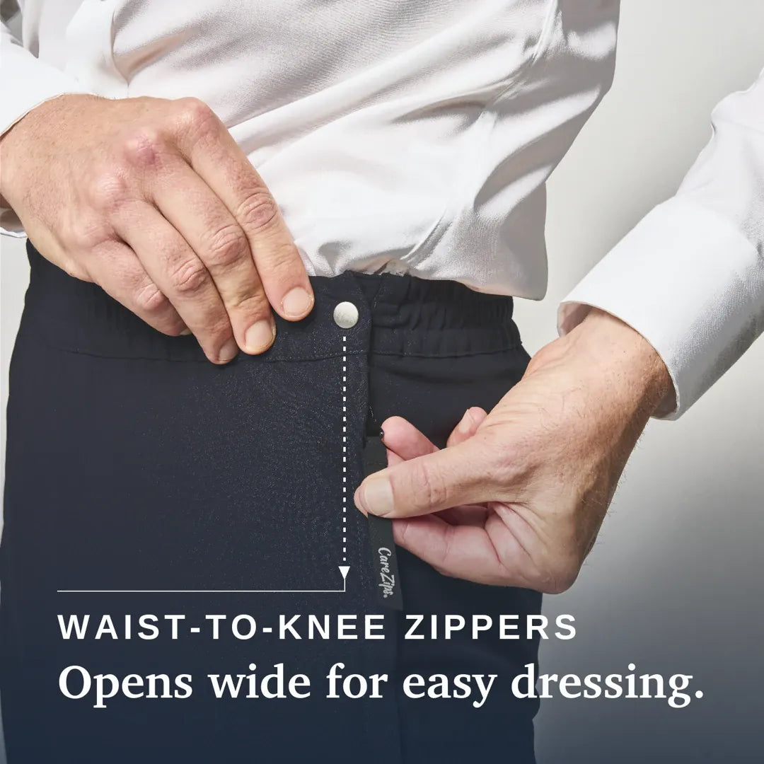 ["Close-up of a person wearing dark charcoal knee-high compression or medical pants, demonstrating a waist-to-knee zipper that opens wide. The person is wearing a white dress shirt. Joe & Bella CareZips® Men's Adaptive Pants ", "Black"]