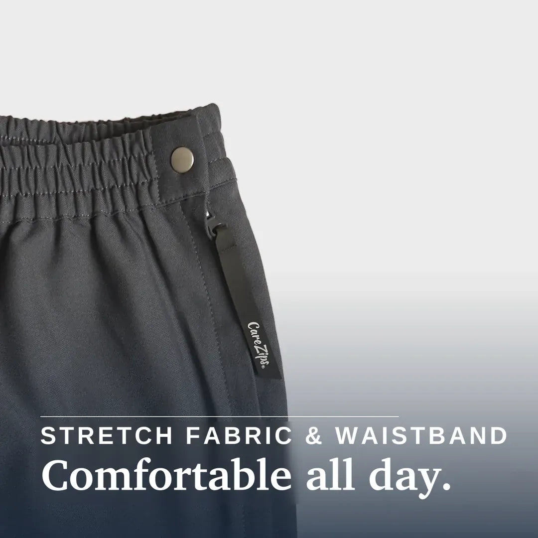 ["A close-up of a person wearing gray elastic-waist pants, pulling the fabric outward with one hand to demonstrate stretch. The person is also wearing a blue and white checkered shirt. Joe & Bella CareZips® Men's Access Pants ", "Slate Grey"]