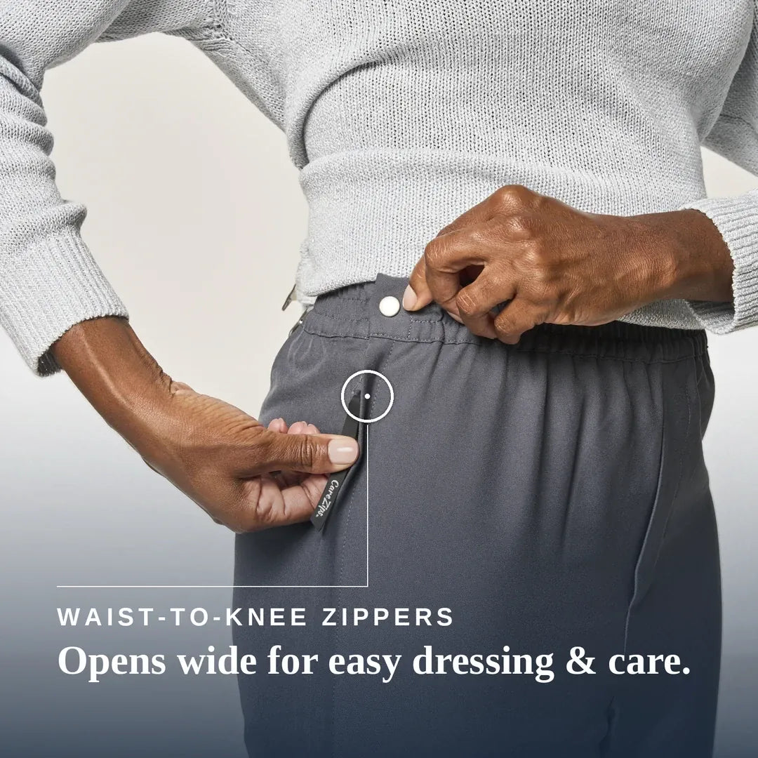 Close-up of a person wearing dark gray waist-to-knee zippers pants, demonstrating how easily the waistband can be opened wide. The person is also wearing a light gray knit sweater. Joe & Bella CareZips® Women's Access Pants #Grey