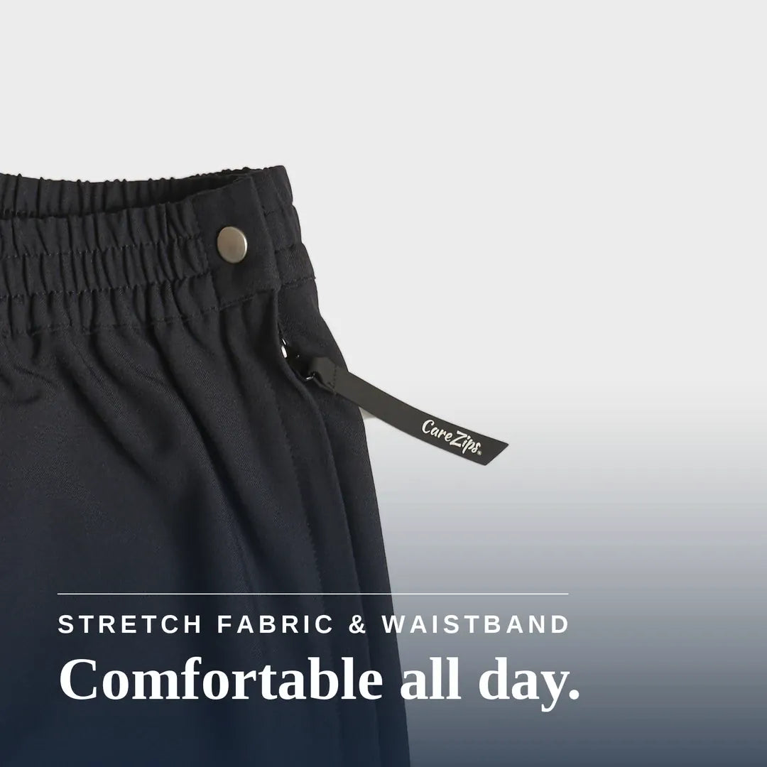 Close-up of dark charcoal gray or black athletic pants showing the elastic waistband, a metal snap button, and a drawstring with a visible CareZip tag. Text overlay at the bottom reads 'STRETCH FABRIC & WAISTBAND Comfortable all day. Joe & Bella Black / XS CareZips® Women's Adaptive Pants #Black