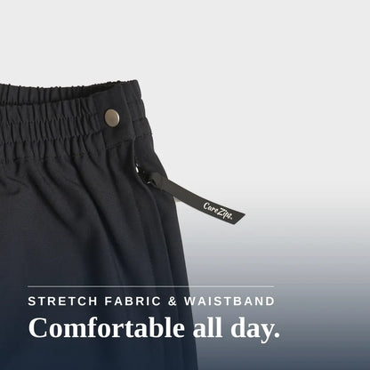 Close-up of dark charcoal gray or black athletic pants showing the elastic waistband, a metal snap button, and a drawstring with a visible CareZip tag. Text overlay at the bottom reads 'STRETCH FABRIC & WAISTBAND Comfortable all day. Joe & Bella Black / XS CareZips® Women's Adaptive Pants #Black