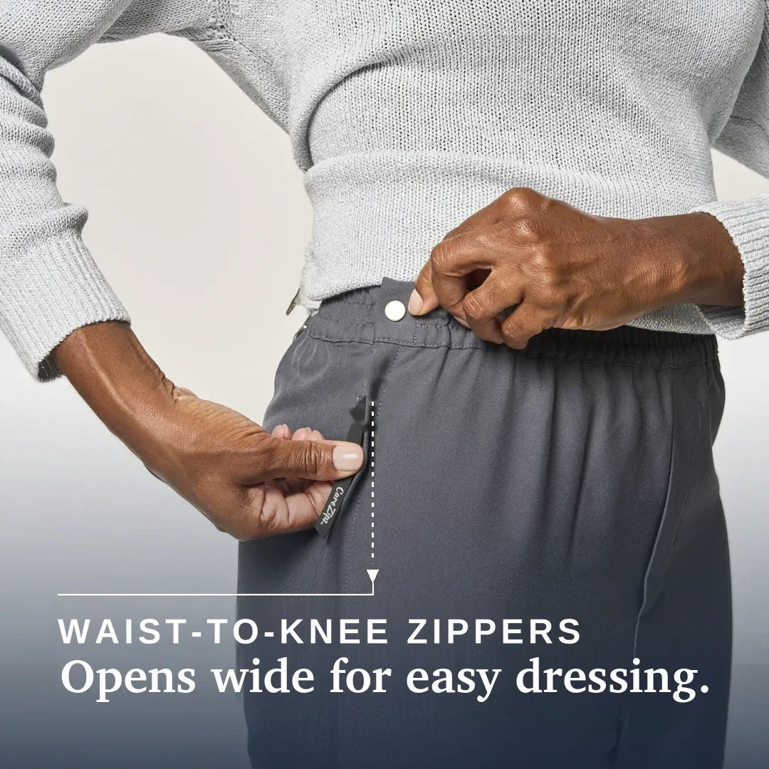 Close-up of a person wearing dark gray waist-to-knee zippers pants, demonstrating how easily the waistband can be opened wide. The person is also wearing a light gray knit sweater. Joe & Bella CareZips® Women's Access Pants #Grey