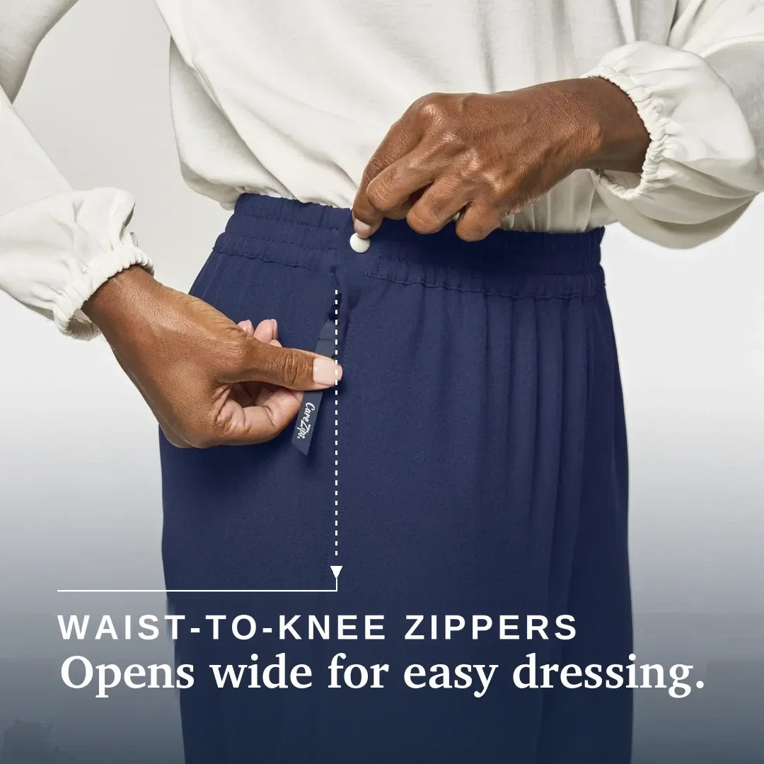 ["A close-up of a person wearing navy blue waist-to-knee zippers pants, demonstrating how easily the waistband can be opened. The person is wearing a white long-sleeve blouse, and the image includes the text 'WAIST-TO-KNEE ZIPPERS Opens wide for easy dressing & care. Joe & Bella CareZips® Women's Access Pants ", "Navy"]