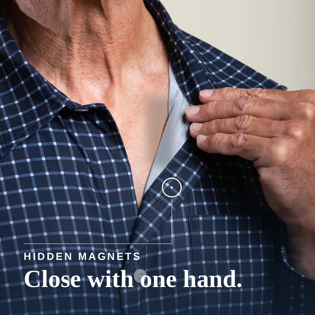 ["Close-up of a man's neck and chest wearing a navy and white plaid button-up shirt, with his hand reaching toward a small hidden magnet near the collar. Text on the image reads 'HIDDEN MAGNETS Close with one hand. Tailored-Fit ", "Navy Check"]