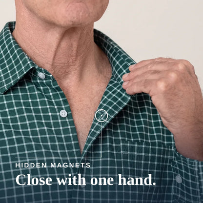 Close-up of a man wearing a green and white plaid button-up shirt, pulling the collar slightly with his right hand. A small inset circle highlights a hidden magnetic area at the collar. | Tailored-Fit#Green Check