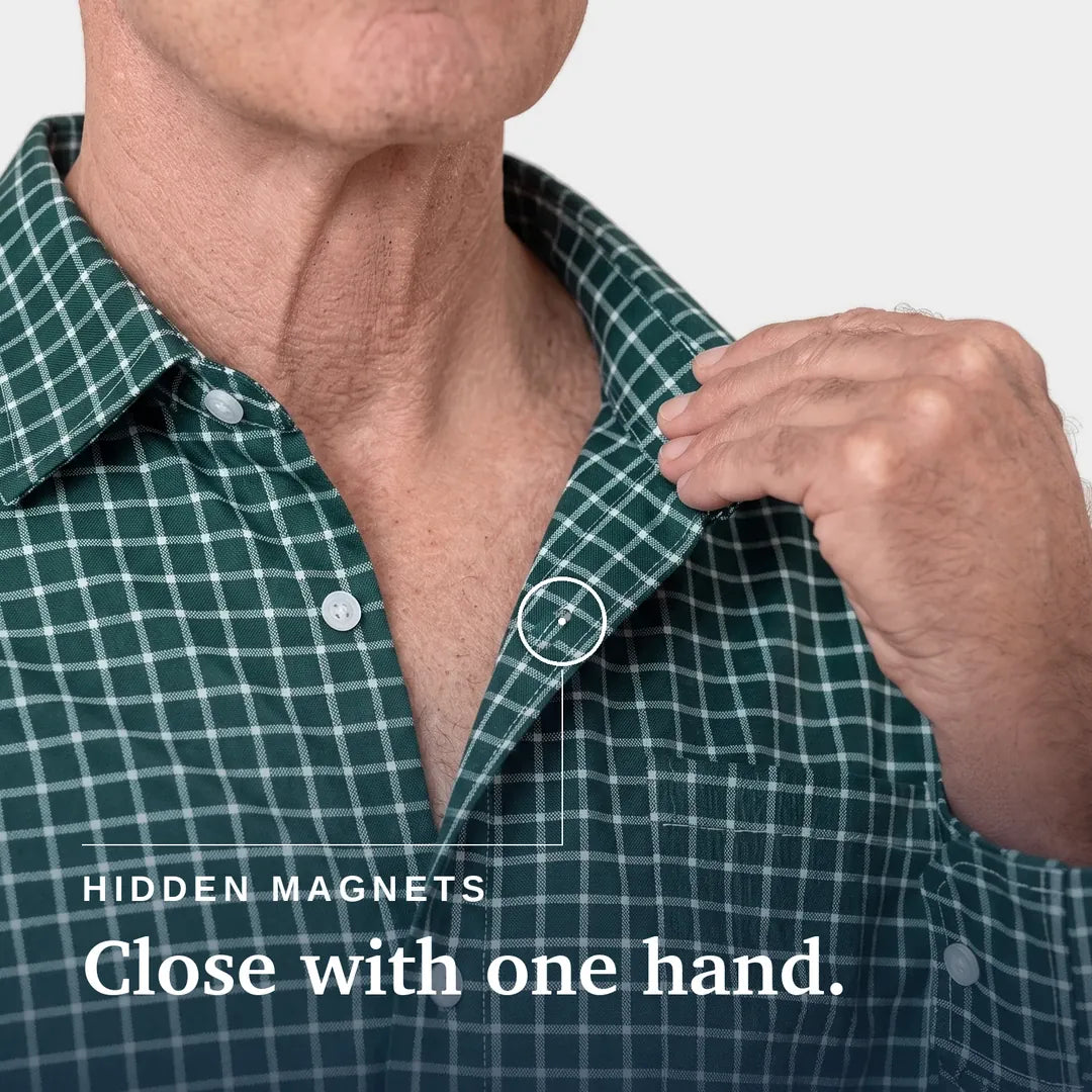 ["Close-up of a man wearing a green and white plaid button-up shirt, pulling the collar slightly with his right hand. A small inset circle highlights a hidden magnetic area at the collar. | Tailored-Fit", "Green Check"]