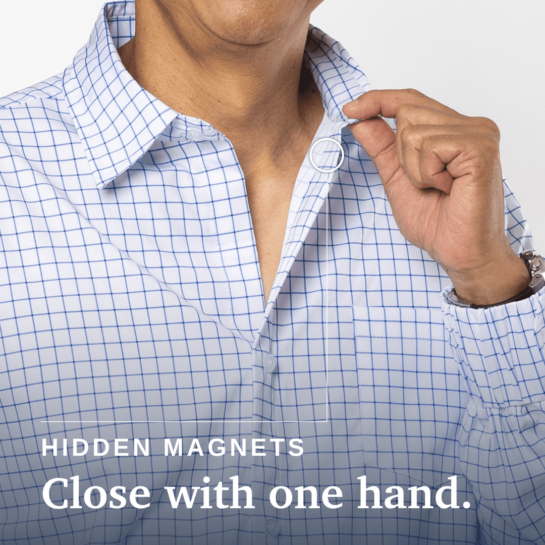 Close-up of a person wearing a white button-up shirt with a blue grid pattern, opening the collar with one hand. White text at the bottom reads 'HIDDEN MAGNETS Close with one hand. Joe & Bella Everyday Magnetic Button-Down for Men | Tailored-Fit #White Check