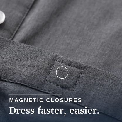 Close-up of a dark gray textured fabric garment showing a stitched pocket or tab with a circular callout and the text 'MAGNETIC CLOSURES Dress faster, easier.'. | Tailored-Fit #Heathered Grey