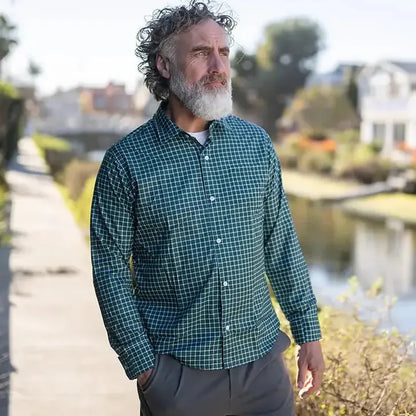 A man modeling a green and black checkered long-sleeve button-down shirt, paired with tan pants, a black belt, and black sneakers, standing against a plain white studio background. #Green Check
