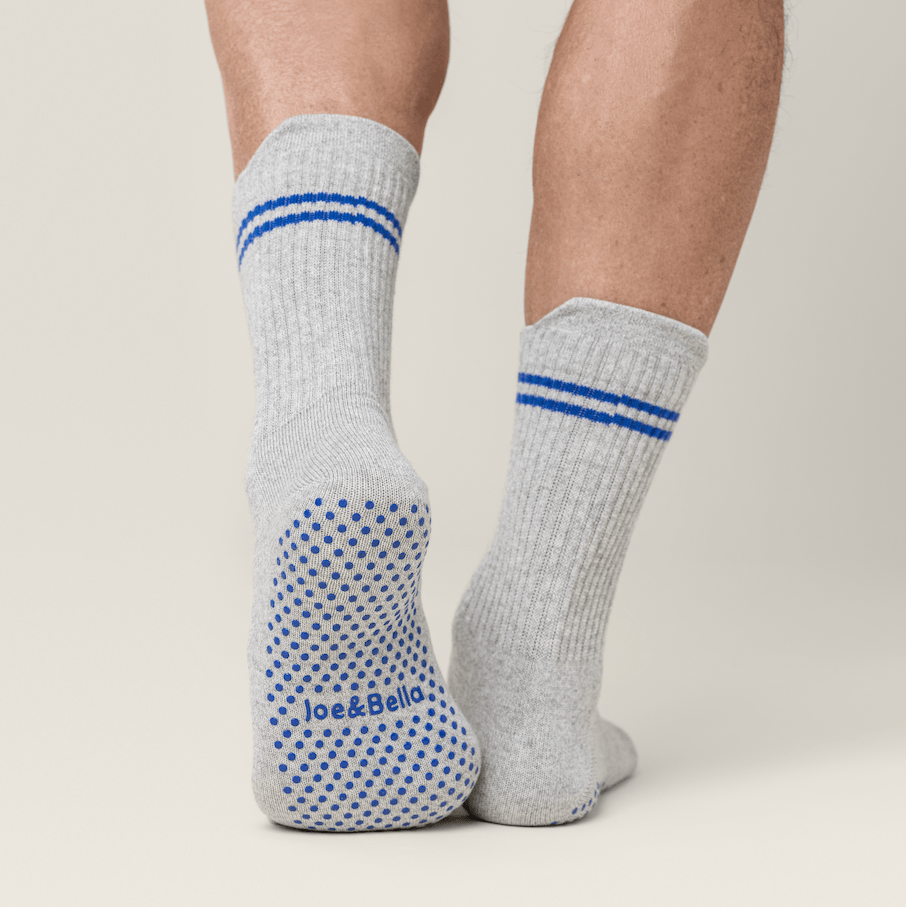 ["Gray socks with blue stripes and patterns worn by a person on a plain background ", "grey"]