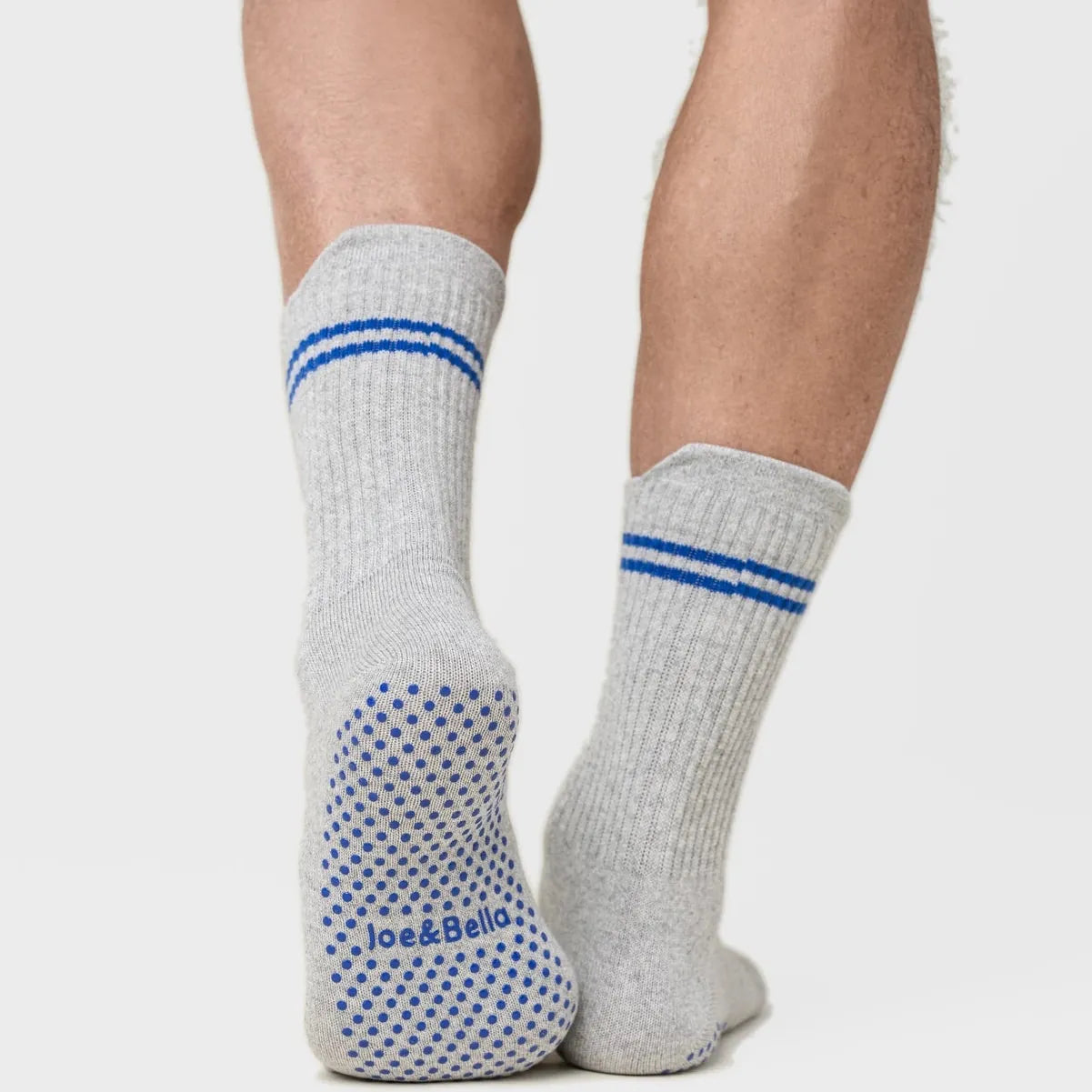 Gray socks with blue stripes and patterns worn by a person on a plain background #Grey