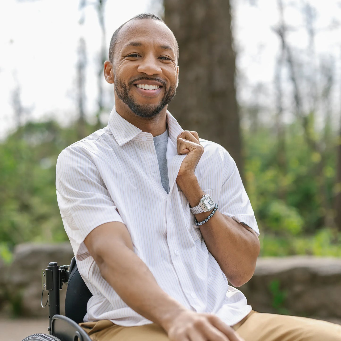 Man in a wheelchair sitting outdoors with trees in the background #Tan 