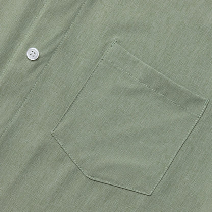 Close-up of a green shirt pocket with a button on a matching fabric background #Green