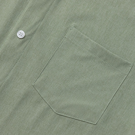 Close-up of a green shirt pocket with a button on a matching fabric background #Green