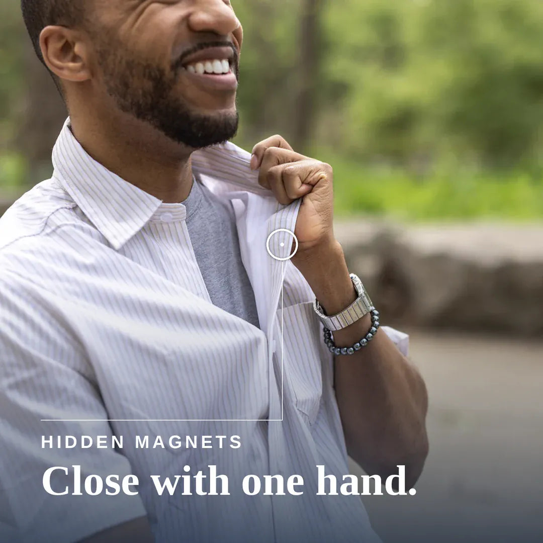 ["A smiling man in a white pinstripe button-down shirt adjusts the collar with one hand, with a small circular inset showing a hidden magnet feature. Text on the image reads 'HIDDEN MAGNETS Close with one hand. ", "Tan Stripe"]