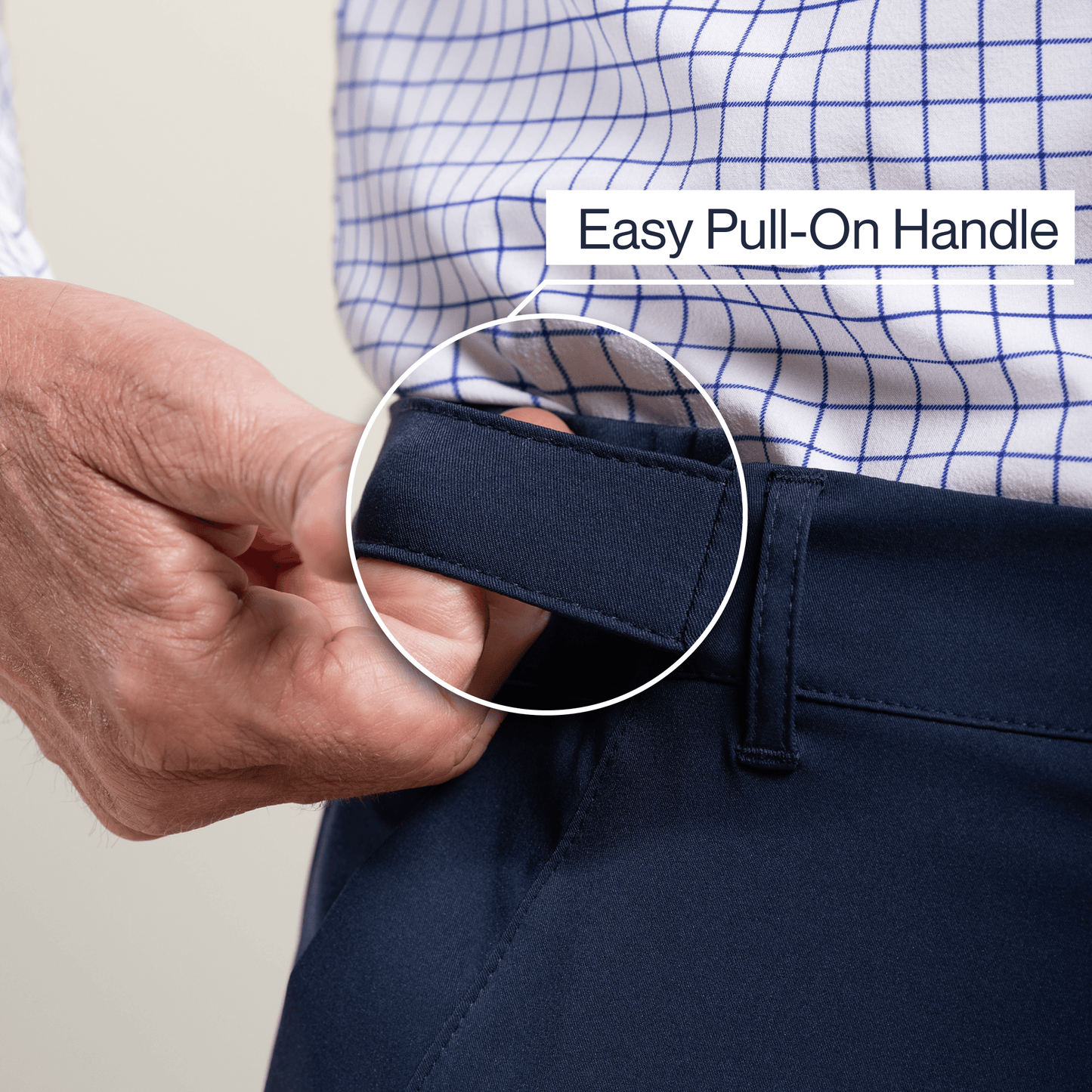 Person adjusting navy pants with an easy pull-on handle, wearing a checkered shirt. #Navy