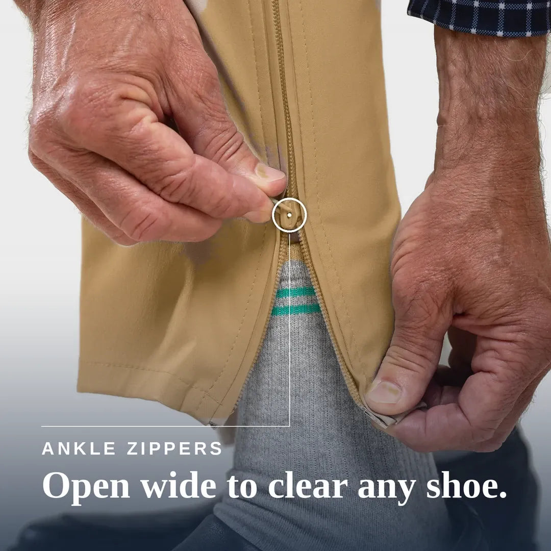 Close-up of a person's hands demonstrating an ankle zipper on a tan garment, with text reading 'ANKLE ZIPPERS Open wide to clear any shoe.'. Joe & Bella Signature Side-Zip Chinos for Men #Khaki
