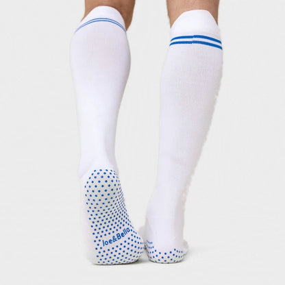 White knee-high compression socks with blue stripes at the top and blue grip dots on the sole, shown on a model's legs against a light gray background. Joe & Bella Big-Grip No-Slip Compression Socks: 3-Pack #White