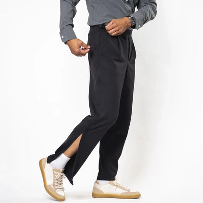 A model wearing black pinstriped trousers with a side slit, styled with a gray button-down shirt, white socks, and beige sneakers, shown from the waist down against a white studio background. Joe & Bella Black / S Everyday Side-Zip Pants for Men #Black