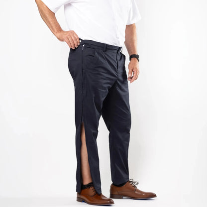 A man wearing dark navy trousers with a front slit, styled with a white polo shirt and brown leather dress shoes, photographed against a clean white studio background. #Navy